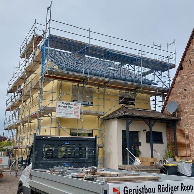 Einfamilienhaus mit Baugerüst und Handwerkerfahrzeug vor dem Eingang