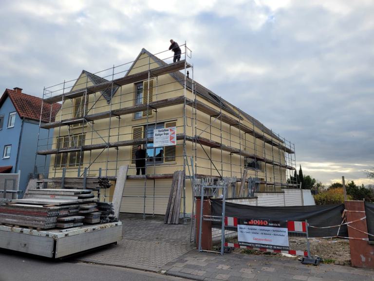 Mehrfamilienhaus mit Gerüst und Baumaterialien während einer Fassadenrenovierung