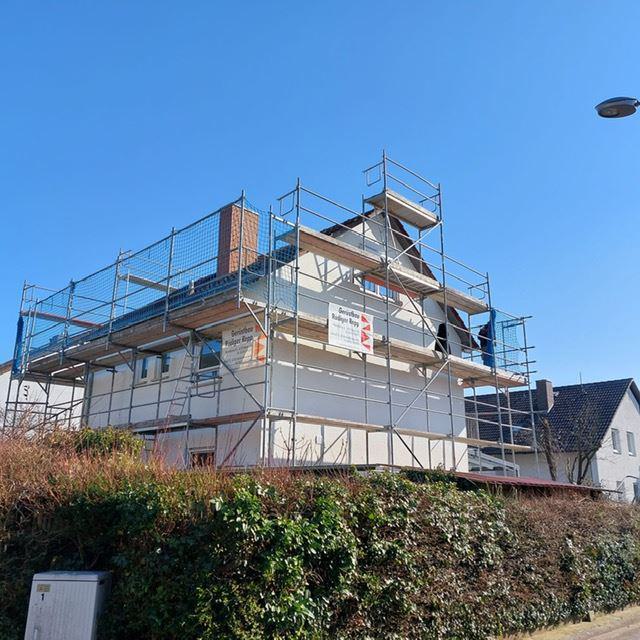 Haus mit Gerüst während einer Sanierung unter blauem Himmel